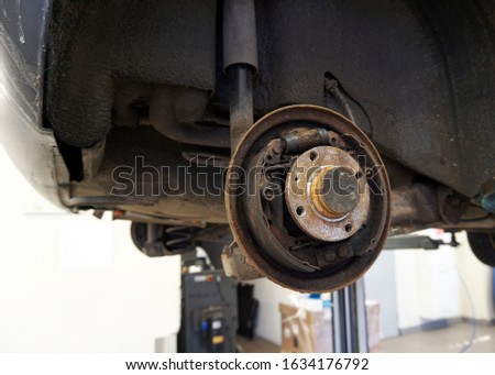 Old worn rusted rear brake of a car. The car is lifted on a lift in service to repair or replace the brake mechanism. Serviceable brakes mean road safety.