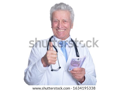Senior male doctor holding money and showing ok sign against white background