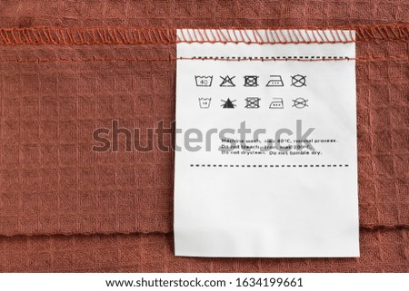 Care clothes label on brown cotton background closeup