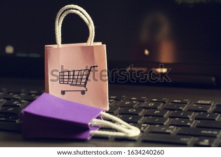 Online shopping concept: Two paper shopping bags on notebook keyboard. E-commerce is the purchase of products and services on the internet can purchase goods or services foreign country.