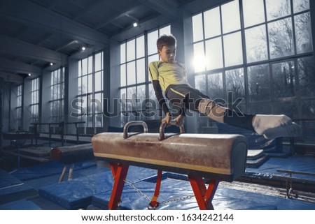 Little male gymnast training in gym, flexible and active. Caucasian fit little boy, athlete in sportswear practicing in exercises for strength, balance. Movement, action, motion, dynamic concept.