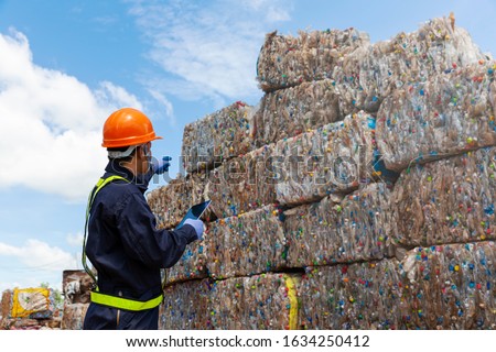 The engineer is pointing the finger to order the job. Engineer and recycle. Engineers standing in recycling center. back view of Male foreman wearing protective equipments and holding tablet. Royalty-Free Stock Photo #1634250412