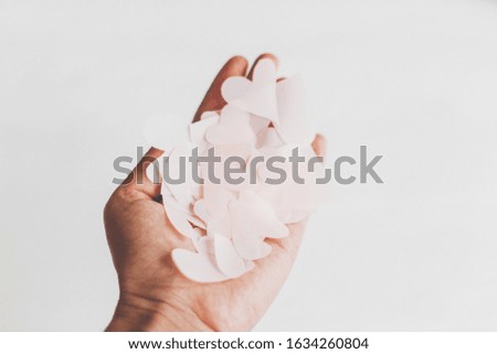 Happy valentines day. Hand holding cute pink pastel hearts on white  background with space for text.  Stylish gentle image. Pink paper heart cutouts ,  greeting card. Selective focus