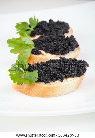 Small sandwiches with black caviar on white plate