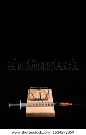 Mousetrap with a bait in the form of a syringe. Stock photo concept of addiction / diabetes.