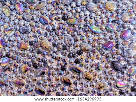 Glossy pebble tiles with rainbow shimmer. Decorative panel made of smooth stones.