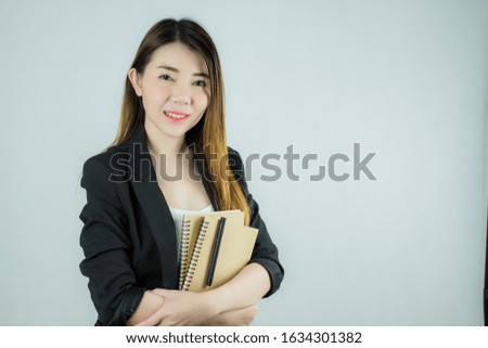 Portrait of beautiful asian business woman holding a notebook and pen. Caucasian female model isolated on white background.