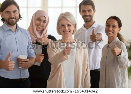 Portrait of smiling diverse multiracial colleagues look at camera pose for group picture show thumbs up recommend good service or company, happy multicultural employees give sincere recommendation