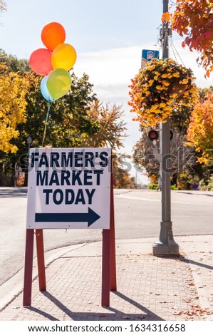 A vertical shot of a sign on the street directing people to Farmer's Market