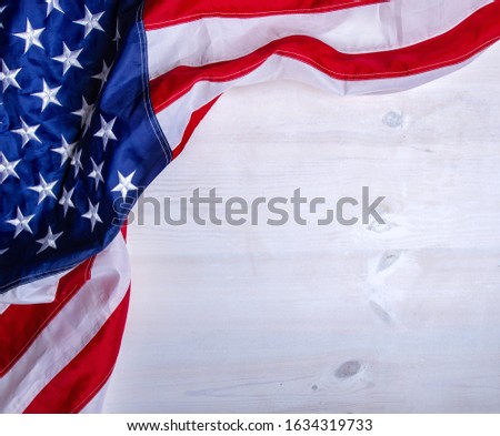 The star-striped flag of the United States of America lies on wooden boards forming a frame for text.