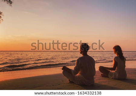 meditation and relaxation for couple, yoga group on the beach at sunset