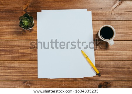 A4 blank paper, cup of coffee on wooden table background. Blank branding template.Photo blank form. Mock up for portfolio design.