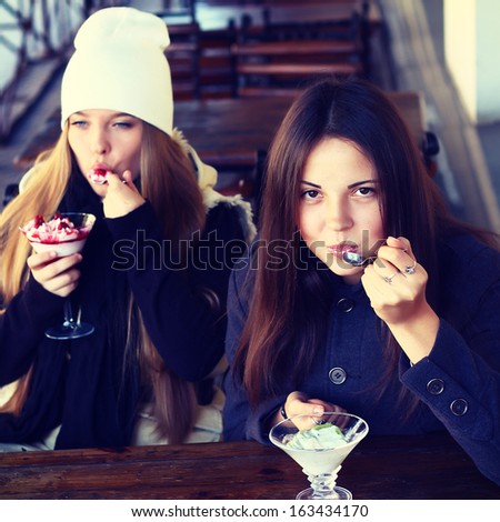 Two young teenage girls eat desserts in the city cafe