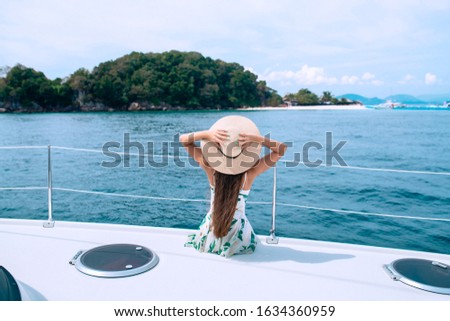 Back view picture of young amazing woman wearing hat sitting on the yacht and looking on the seascape
