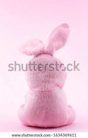 toy pink rabbit on a pastel pink background with a place for the inscription. Plush Bunny with Easter , the Easter Bunny , back in the frame