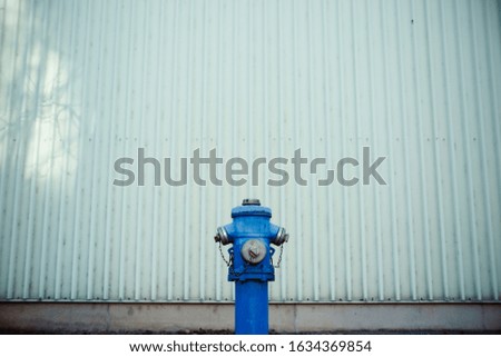 Blue water hydrant in front of a green wall. Emergency, safety and protection concept.