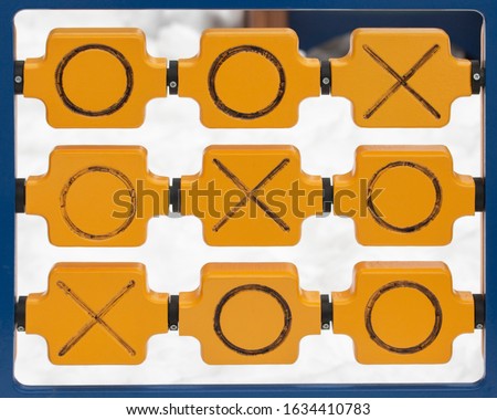 Wooden game tic tac toe on outdoor playground. Cross zero game noughts and crosses on a winter snowy ground. Tic tac toe winning combination diagonally Xs and Os