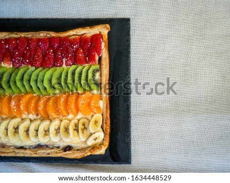 Chocolate and cream based puff pastry cake, coated with natural kiwi, strawberry, banana and tangerine