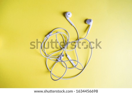 earphones for a mobile phone on a yellow background
