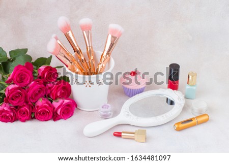 on the table is a mirror, a bouquet of pink roses, brushes and makeup 