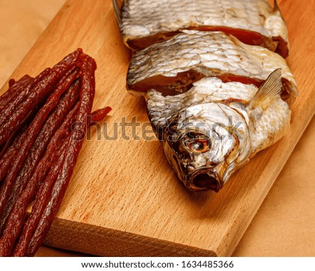 Dried fish with caviar and snacks on a cutting board.