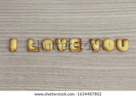 I LOVE YOU sentence arranged with cookies ABC on white oak wooden background for valentine's day.