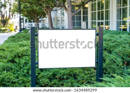 White company sign mockup in a garden.
