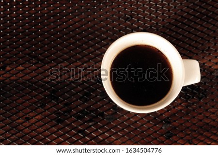 Coffee in white mug on black grid. Horizontal photo with copy space to the left.