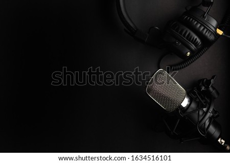 Studio black studio microphone with studio headphones on a black background. Banner. Radio, work with sound, podcasts.