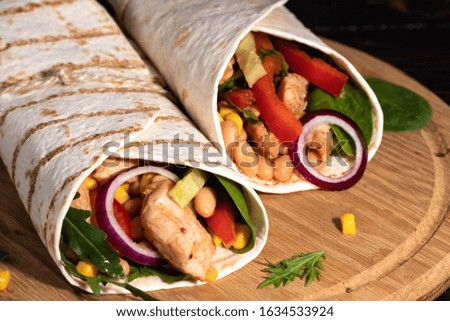 Burritos wraps with chicken and vegetables on dark background. Mexican food.