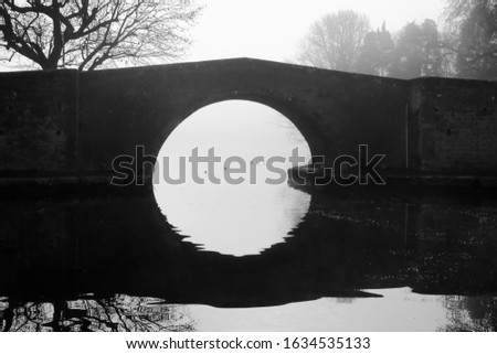Black and white photography of an old stone bridge crossing the Midi canal in France on a foggy day