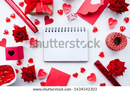 
Valentine's Day. Flat lay of red hearts, handmade gift boxes, red roses and a notebook for writing on a white background. Copy space. The concept of holidays and love.
