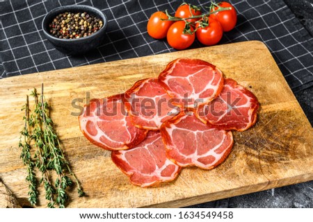 Raw smoked meat Jamon Lomo. Black background. Top view Royalty-Free Stock Photo #1634549458