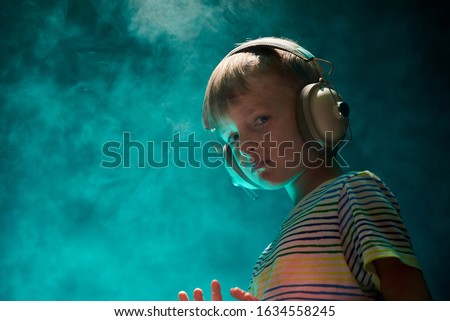 Little boy listens to his favorite music in modern wireless headphones