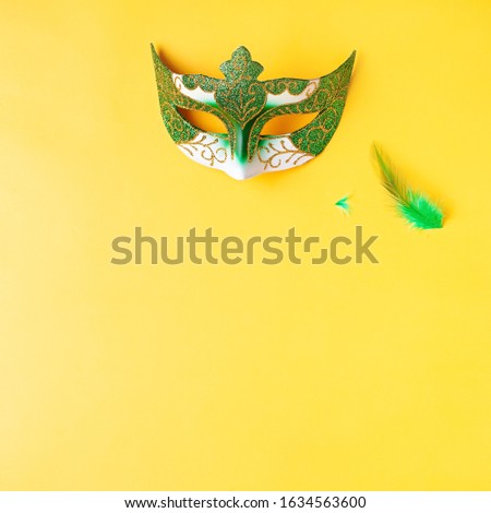 Mardi gras accessories flat lay on bright yellow background, top view, copy space. Frame with traditional Mardi gras beads, masks, feathers flat. Carnival holiday concept overhead