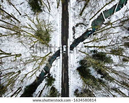 An aerial overhead shot a narrow road in mountains near Steven's pass with a vehicle in the center in Seattle, Washington DC, USA