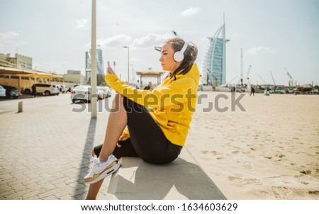 It's time for a selfie. A young woman in a yellow sweatshirt takes a selfie picture on the beach 