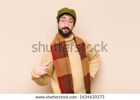 young cool bearded man looking proud, confident and happy, smiling and pointing to self or making number one sign