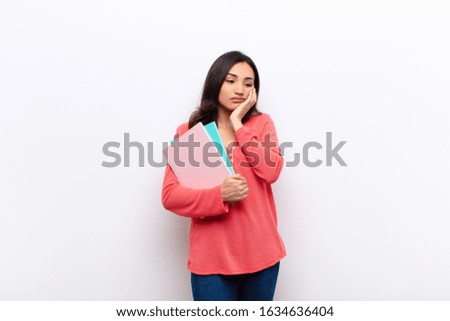 young latin pretty woman  against flat wall with books