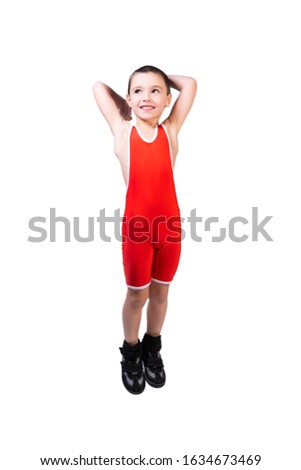 Little smiling boy with dark hair in a red sports tight   jumping and having fun on an isolated white background in a photo studio.   The concept of a little fighter athlete. 