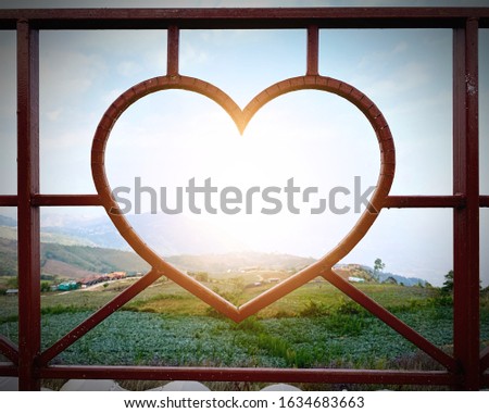 Wrought iron balcony on the roof of the house or resort, bent to a transparent heart shape, looking through a beautiful complex and green of mountain with the morning sunrise, fresh air and good view