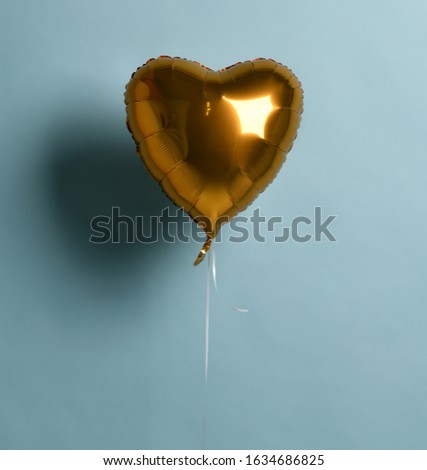 Metallic foil single gold heart balloon object for birthday party or valentines day on pastel color light blue background