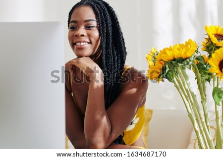 Smiling creative young Black woman working on computer at her desk