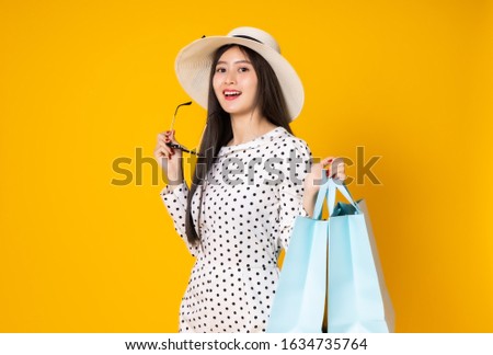 Asian woman in summer casual clothes.She smiling and  happy shopping bags. she  lovely attractive shine on  yellow background.Summer Surprise Sale  concept.