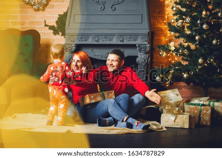 Beautiful mother in a red sweater. Family sitting near christmas gifts. Little boy near christmas tree