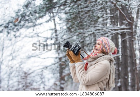 taking picture in winter forest. Photographer photographing on snowy winter day. happy woman warm clothes fashion. winter travel vacation. stylish hipster traveler. woman holding photo camera.