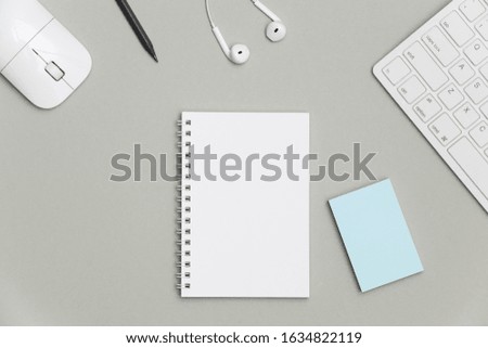 Blank spiral notepad with keyboard, supplies and pencil on gray background. Top view office desk with notepad. Creative flat lay photo