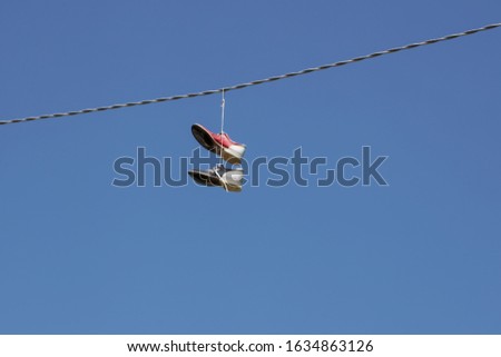 Bowling shoes hanging by shoe laces on an electrical wire with blue sky