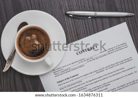 contract signing concept, close-up cup of coffee, silver pen and empty paper sheet of agreement between two counterparties on grey wooden table as background, top view