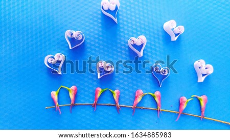 Pretty birds kissing art on a blue background with hearts made up of paper 